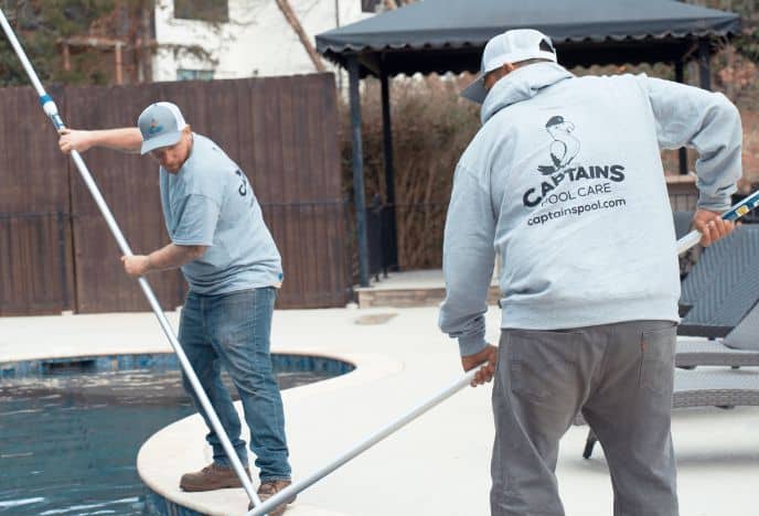 Two men skimming pool