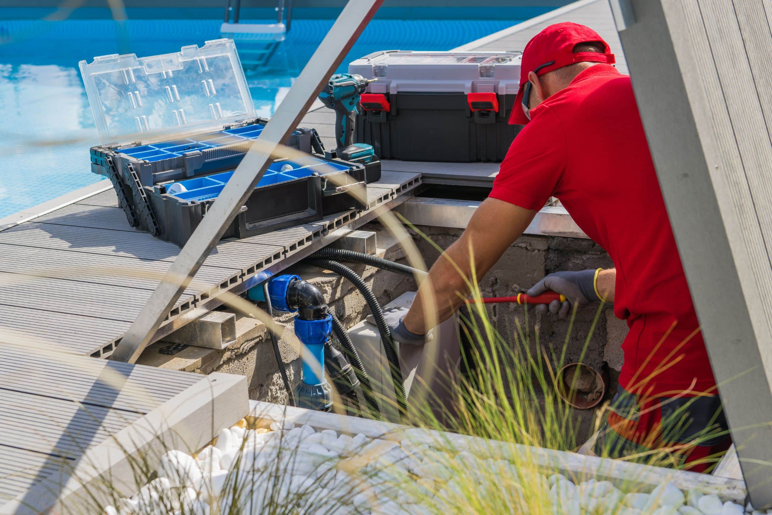 pool maintenance professional in red work clothes working on pool equipment