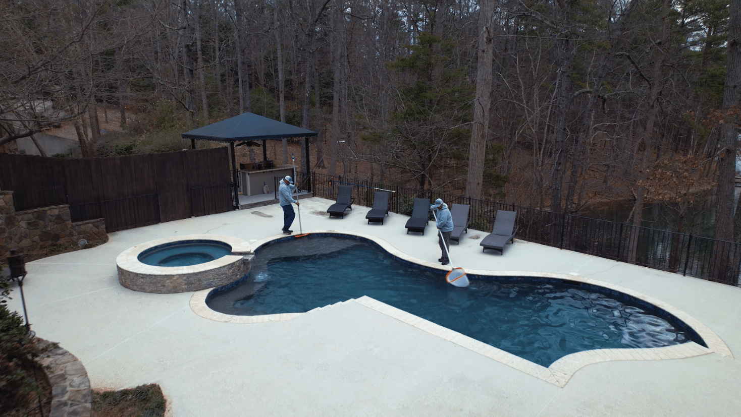 two men cleaning an outdoor pool