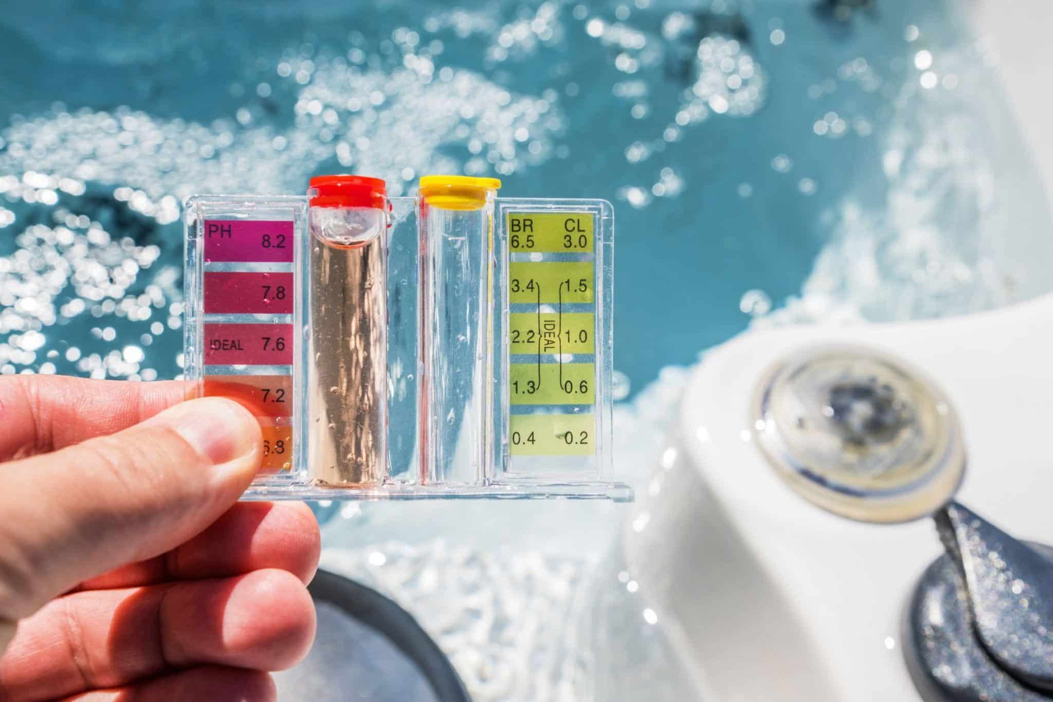 person holding up pool chemical testing strips